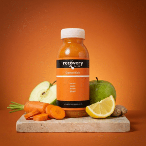 Carrot Kick cold-pressed carrot juice with apple, lemon and ginger on stone slab with vibrant orange background
