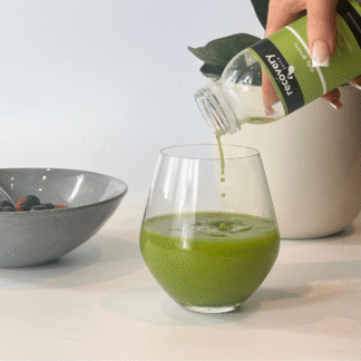 Cold-pressed daily green juice being poured into a glass with a smooth, vibrant texture.