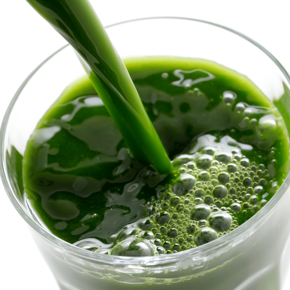 Cold-pressed green juice poured into a glass, rich in nutrients and enzymes for digestion, hydration, and detox support.