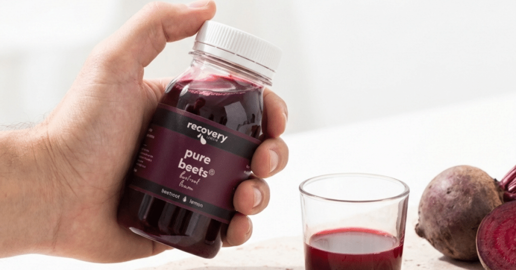 Cold-pressed beetroot juice shot poured from Recovery Juice Pure Beets bottle