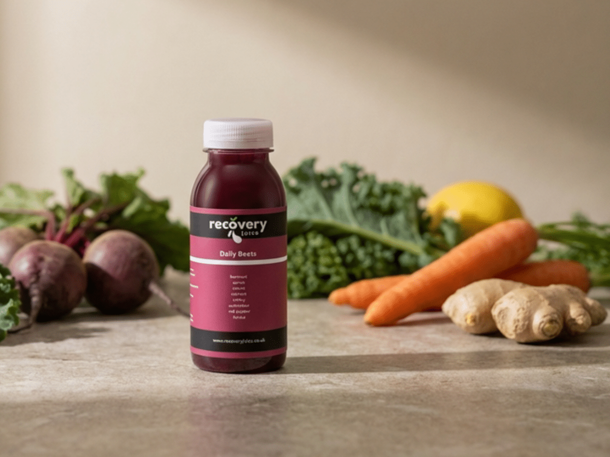 Cold-pressed beetroot juice bottle with fresh beetroot, carrot, ginger and lemon ingredients